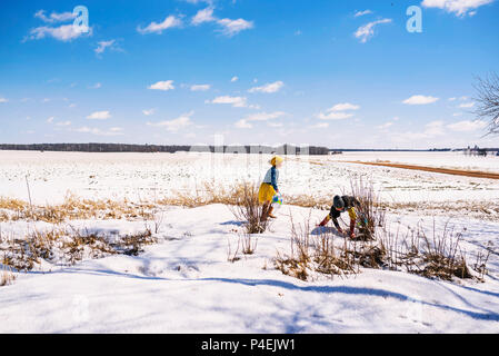 Boy and girl on an Easter egg hunt in the snow Stock Photo