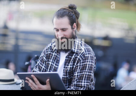 Man sitting outdoors using a digital tablet Stock Photo