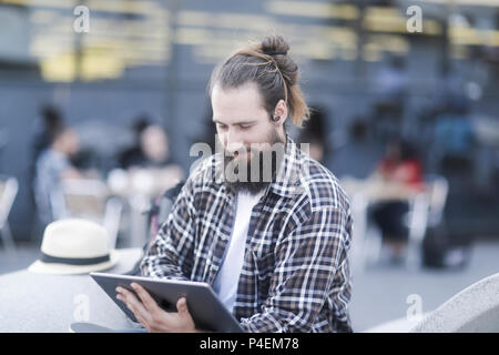 Smiling Man sitting outdoors using a digital tablet Stock Photo