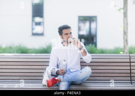 Man sitting on a bench eating lunch Stock Photo
