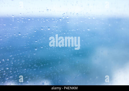 Water droplets on the window of a ship, with a blue sea background Stock Photo