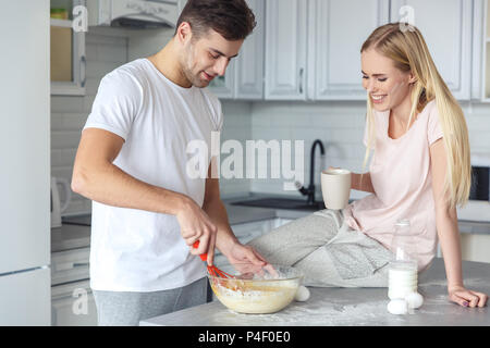 happy young couple cooking breakfast together on kitchen on weekend morning Stock Photo