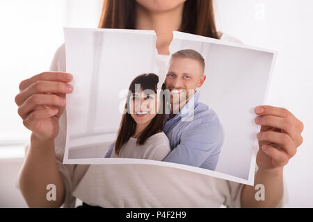 Close-up Of A Woman's Hand Tearing Photo Of Happy Couple Stock Photo