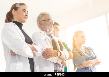 A group of doctors are using a digital tablet for discussing diagnosis and smiling while standing in front of his patient. Stock Photo