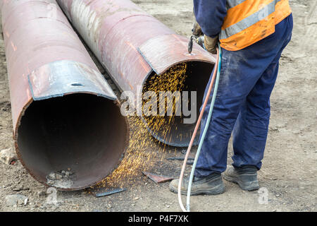 Welder worker cutting hole in metal with oxy acetylene blow torch at at building site. Stock Photo