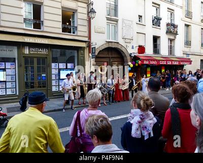 Crowd gathered on an historic street in the lower Marais to enjoy a lively band preforming during the Fête de la musique, Paris, France Stock Photo