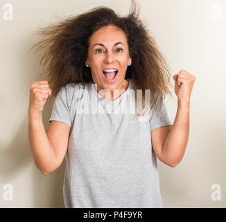 Curled hair brazilian woman screaming proud and celebrating victory and success very excited, cheering emotion Stock Photo