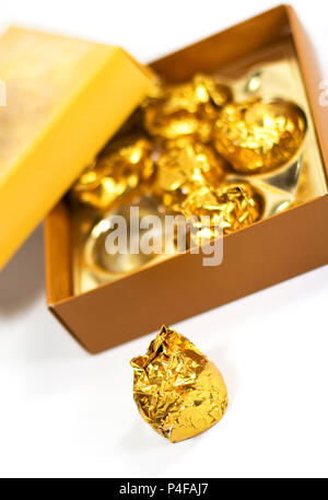 Box Of Round Candies Wrapped Into Golden Foil. One Chocolate Is