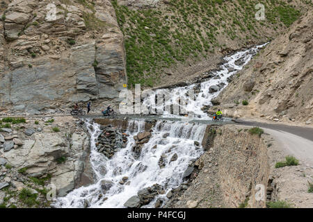 Ladakh, India - July 18, 2017: Biker crossing the river flowing on the road from melting glacier in Himalaya mountains, Ladakh region, India Stock Photo