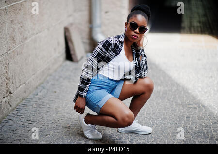 Hip hop african american girl on sunglasses and jeans shorts. Casual street fashion portrait of black woman. Stock Photo
