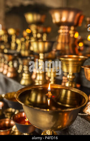 Tibetan Buddhist ritual oil lamp candles close-up in the monastery in Ladakh, India Stock Photo