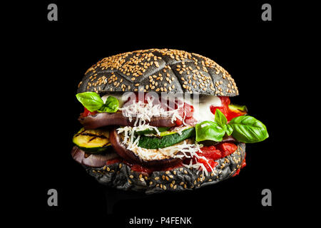 Black burger with Italian stuffing of Parmigiana from eggplants, zucchini and tomato sauce. fresh basil and a lot of cheese. Ideal Italian option for  Stock Photo