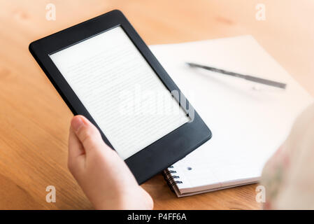 Girl is reading ebook on digital tablet device and is taking notes Stock Photo