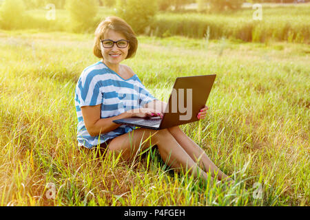 Beautiful woman with a laptop. Smiling at the camera. The picture was taken in the park. Stock Photo