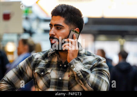 Well groomed man with beard, lumberjack shirt, talking in mobile phone Stock Photo