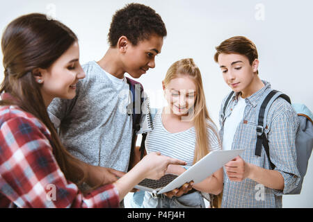 multiethnic group of smiling teenagers using laptop together isolated on white Stock Photo