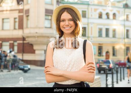 Outdoor portrait of teenager 13, 14 years old, girl with crossed arms, city street background. Stock Photo