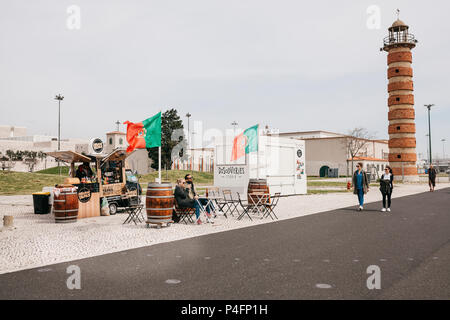 Lisbon, June 18, 2018: Street trade in drinks and food on the waterfront in the Belem area. Young couple man and woman relaxing at table. Other people are walking around Stock Photo