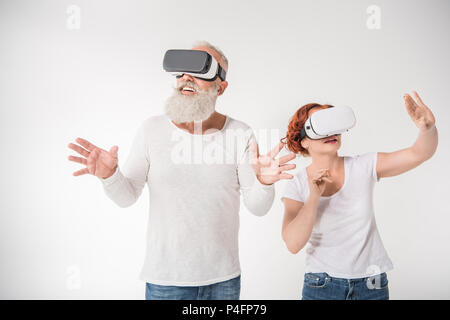 senior couple gesturing and using virtual reality headsets, isolated on white Stock Photo