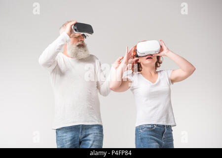 shocked senior couple using virtual reality headsets, isolated on white Stock Photo