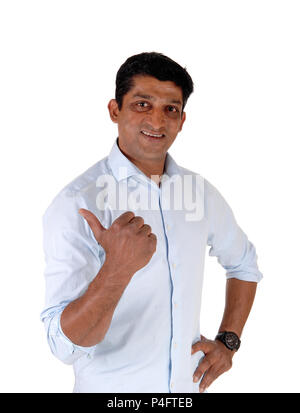 Happy looking man in a blue shirt standing and pointing with his thump, smiling, isolated for white background Stock Photo