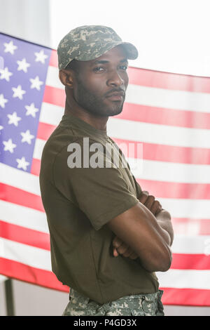 Confident african american man in camouflage clothes in front of us flag Stock Photo