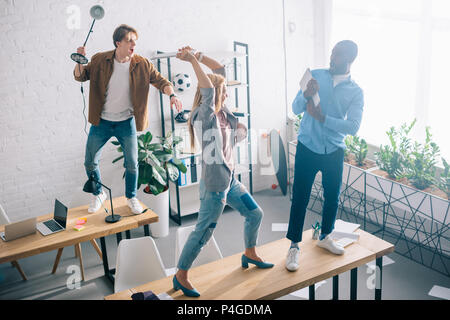 high angle view of two coworkers fighting with african american businessman with laptop in hands in modern office Stock Photo