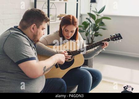 boyfriend teaching girlfriend playing acoustic guitar at home Stock Photo