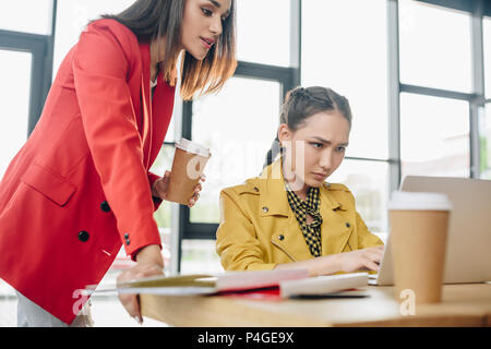Professional businesswomen looking at laptop screen in modern office Stock Photo