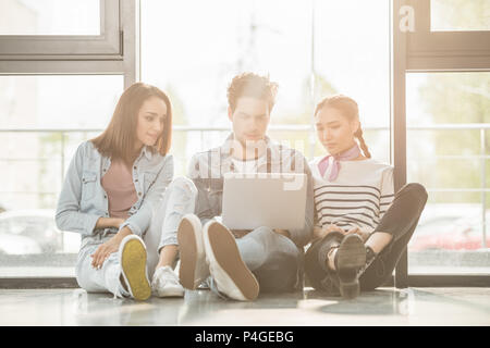 Diverse business team sitting on floor and working with lapotp in light workspace Stock Photo
