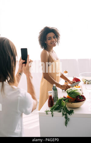 cropped shot of man shooting african american girlfriend on smartphone Stock Photo