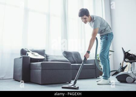 teenager vacuuming floor in living room with vacuum cleaner Stock Photo