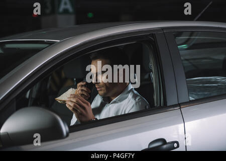 male undercover agent in sunglasses doing surveillance and using talkie  walkie in car Stock Photo