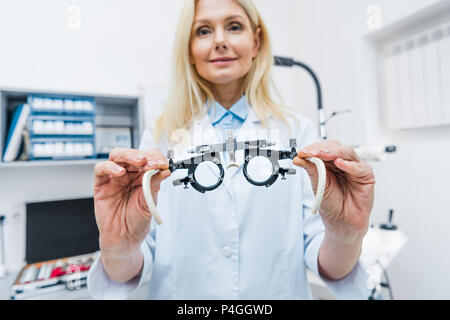 optometrist in white coat holding trial frame in clinic Stock Photo