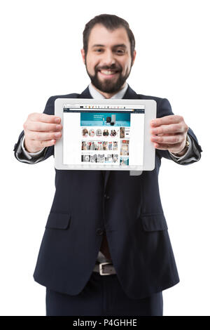 Smiling businessman showing digital tablet with amazon website, isolated on white Stock Photo