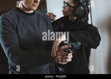 cropped image of instructor describing client how to hold gun Stock Photo