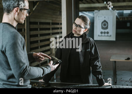 instructor describing gun to female client in shooting range Stock Photo