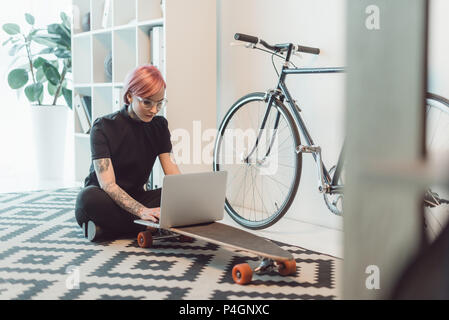 young businesswoman in eyeglasses using laptop on skateboard Stock Photo