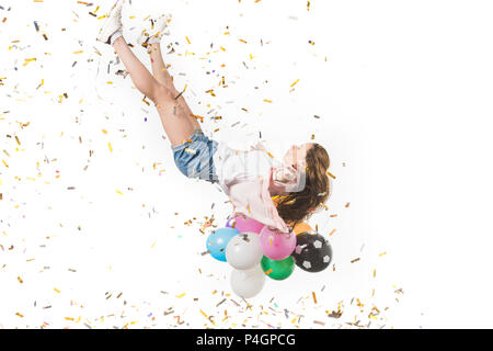young woman with colorful balloons and shiny confetti falling isolated on white Stock Photo