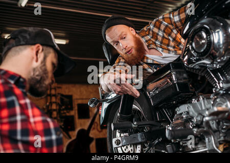 professional mechanics repairing motorcycle together at garage Stock Photo