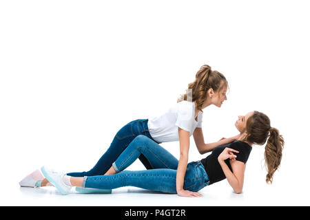side view of attractive young twin cuddling lying on floor sister on white Stock Photo