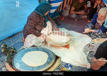 Shiraz, Iran - March 24, 2018: Iranian woman preparing traditional bread on the street market Stock Photo