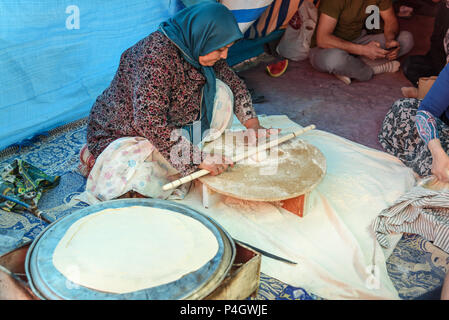 Shiraz, Iran - March 24, 2018: Iranian woman preparing traditional bread on the street market Stock Photo