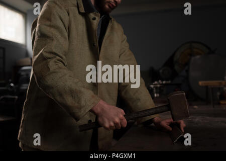 cropped shot of male worker hammering metal part at factory Stock Photo