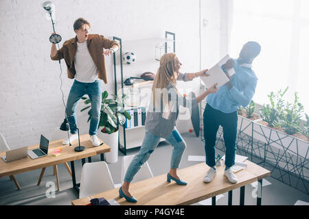 high angle view of multiethnic two colleagues fighting on table in modern office Stock Photo
