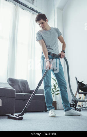 teenager cleaning floor with vacuum cleaner Stock Photo