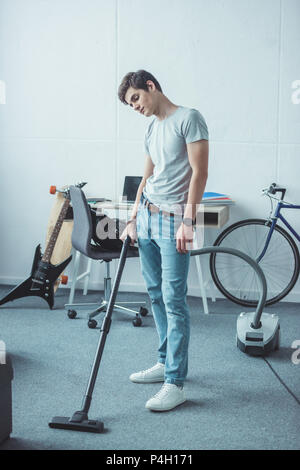 teen boy vacuuming floor in living room Stock Photo