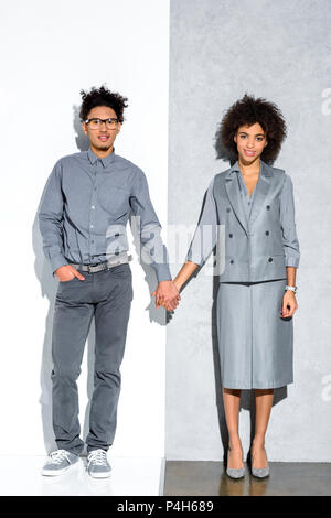 Young african amercian girl and guy holding hands on grey and white background Stock Photo