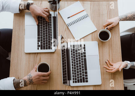 top view of colleagues using laptops and drinking coffee Stock Photo