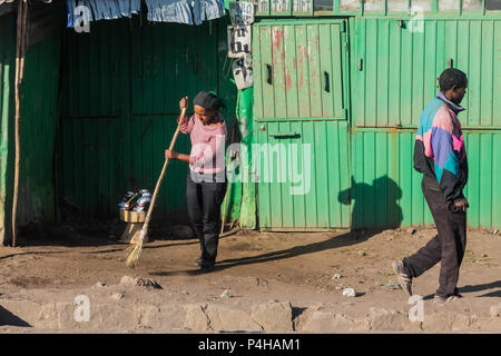 Addis Ababa, Ethiopia, January 30, 2014, Young woman sweeping the front entrance to her informal store in the early morning on a quiet side street Stock Photo